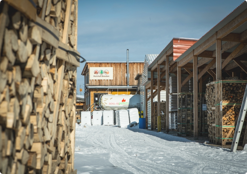 Holzhof Außenansicht mit Holzstapeln im Winter Holzhof Außenansicht mit Holzstapeln im Winter